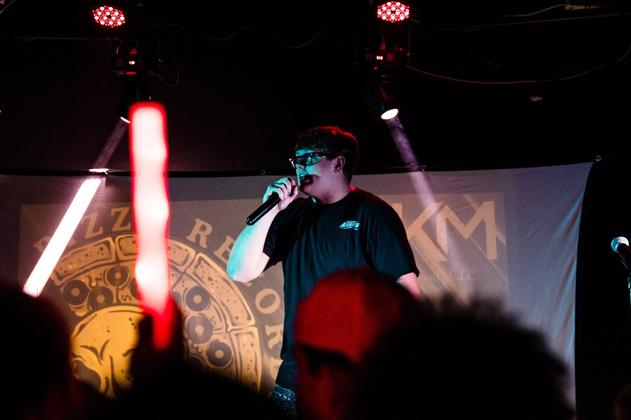 Big4nikk performing live on stage with a microphone.